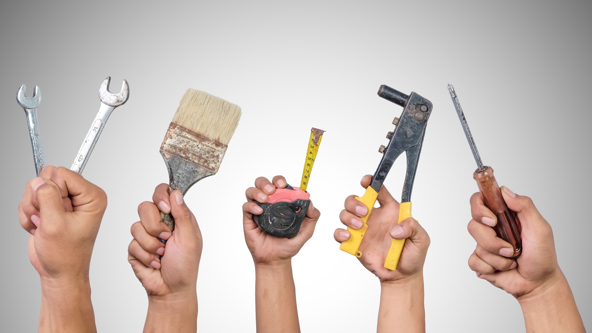 Hands holding different carpentry tools isolated on white background.